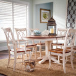 a dining room table with chairs around it. a dining room table with four adams chairs and a lantern resting on table