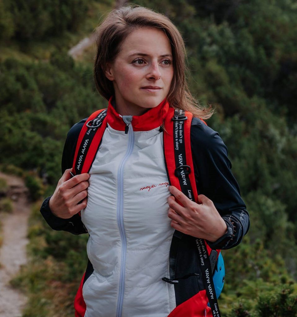 A woman hiking wearing a lightweight ladies' jacket with reflective prints for cross-country skiing, trail running, and trekking in moderate temperatures.