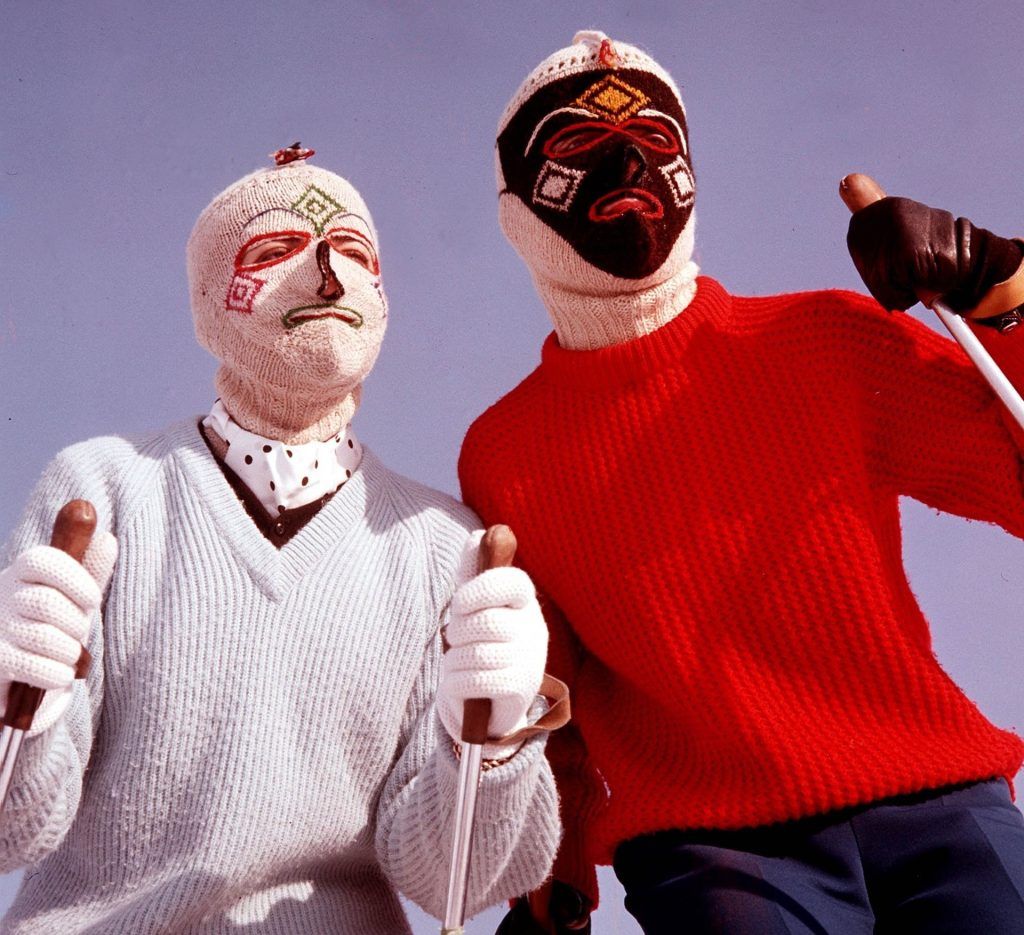 Man and woman skiing with unique ski masks, wearing a funny ski outfit.