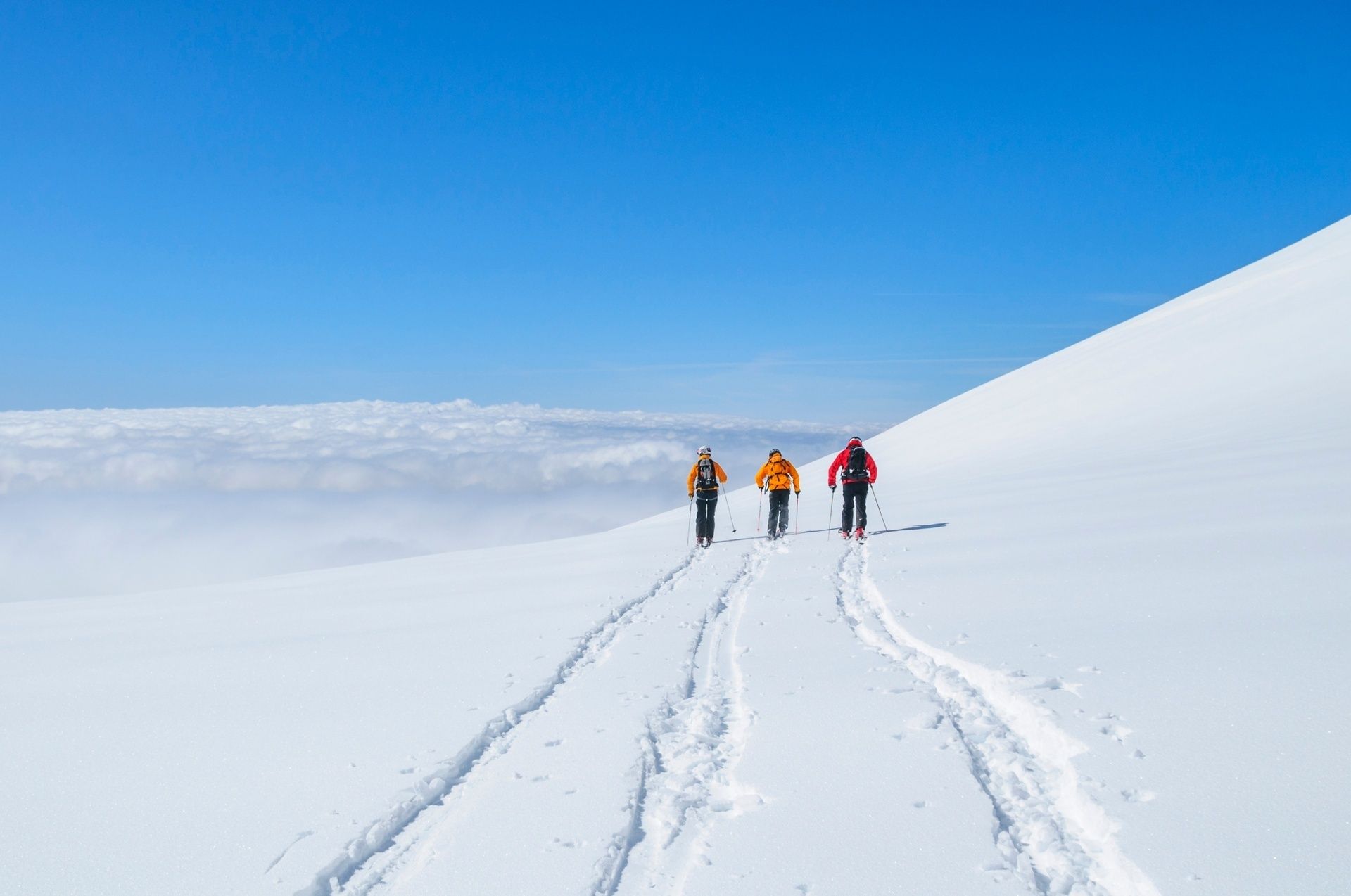 A group of three friends freeride skiing on a snowy mountain top.