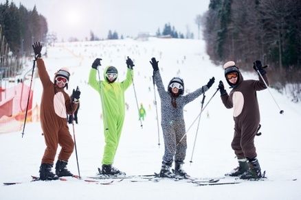 A group of skiiers dressed in funny skiing outfits on a snowy mountain slope.