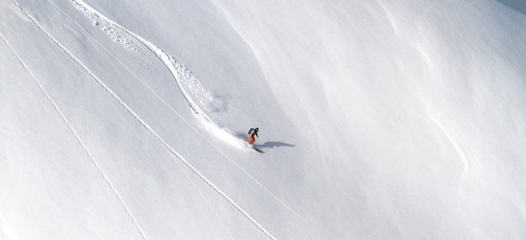 A person freeride skiing down the snowy mountain.