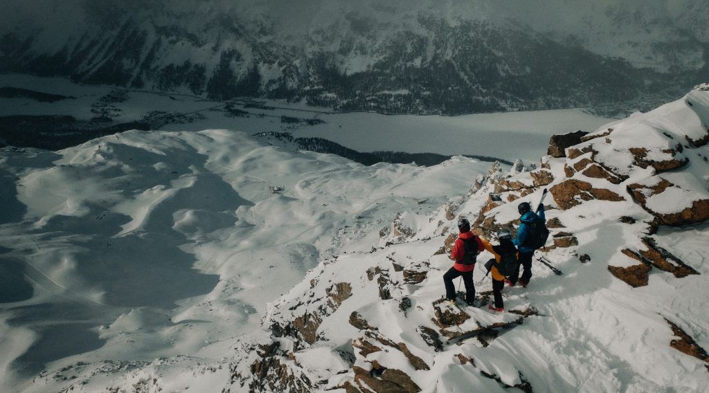 Three people on top of a snowy mountain.