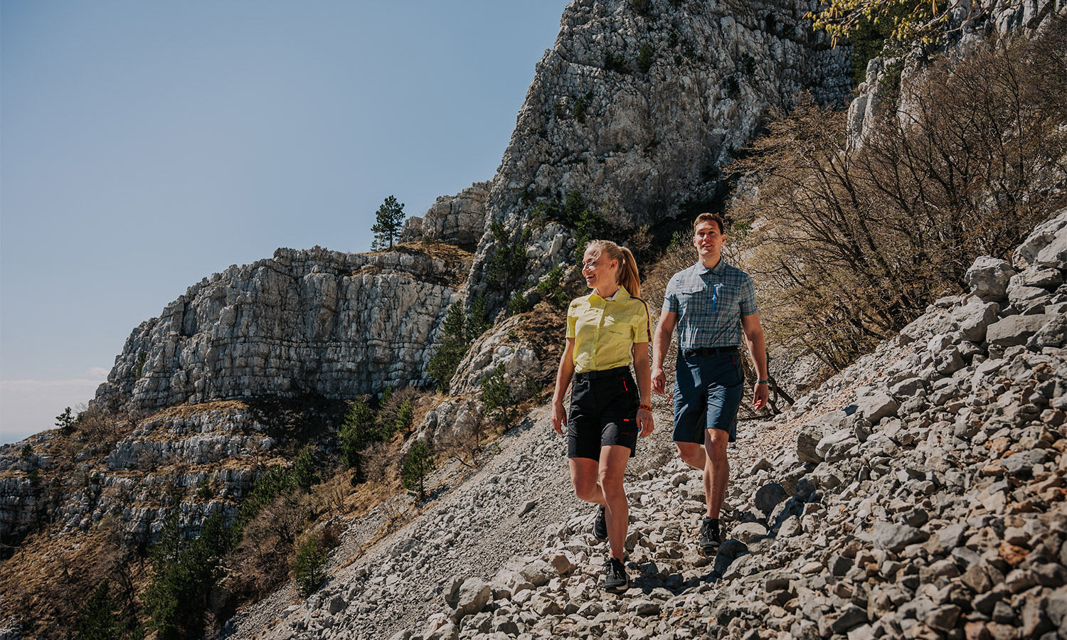 A couple hiking ona sunny day in the mountains in activewear.