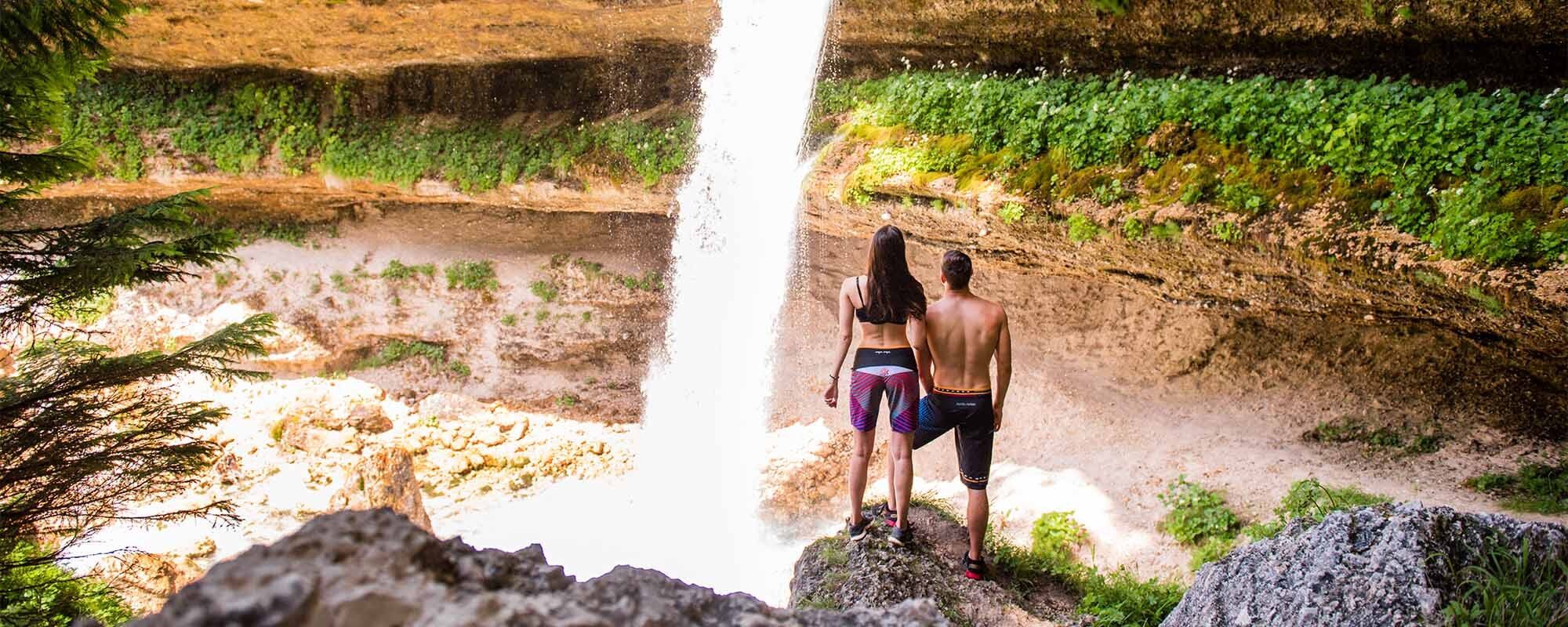A couple standing under the waterfall.