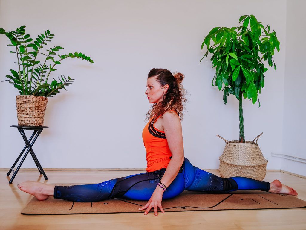 A lady doing yoga split on a yoga mat.