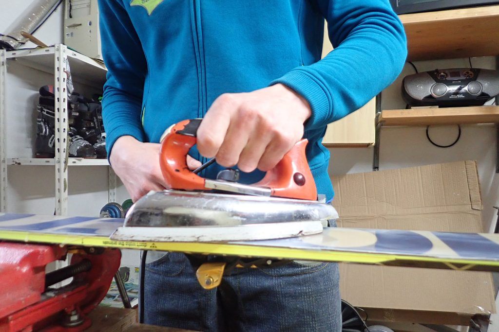 A man applying wax on skis with an iron.
