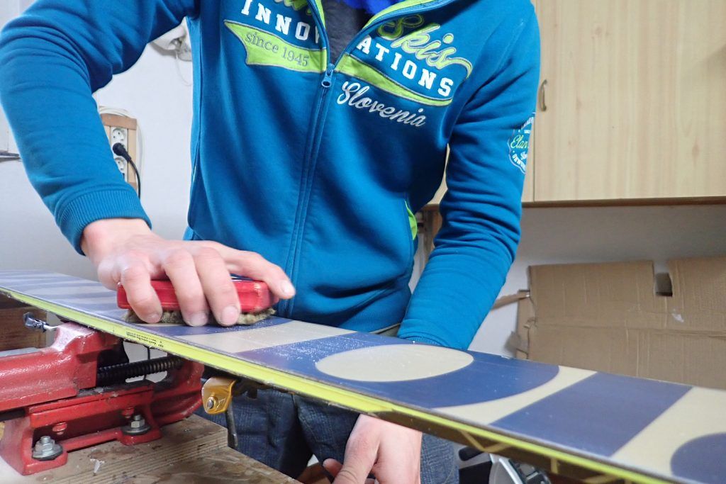 A man brushing wax off of skis.