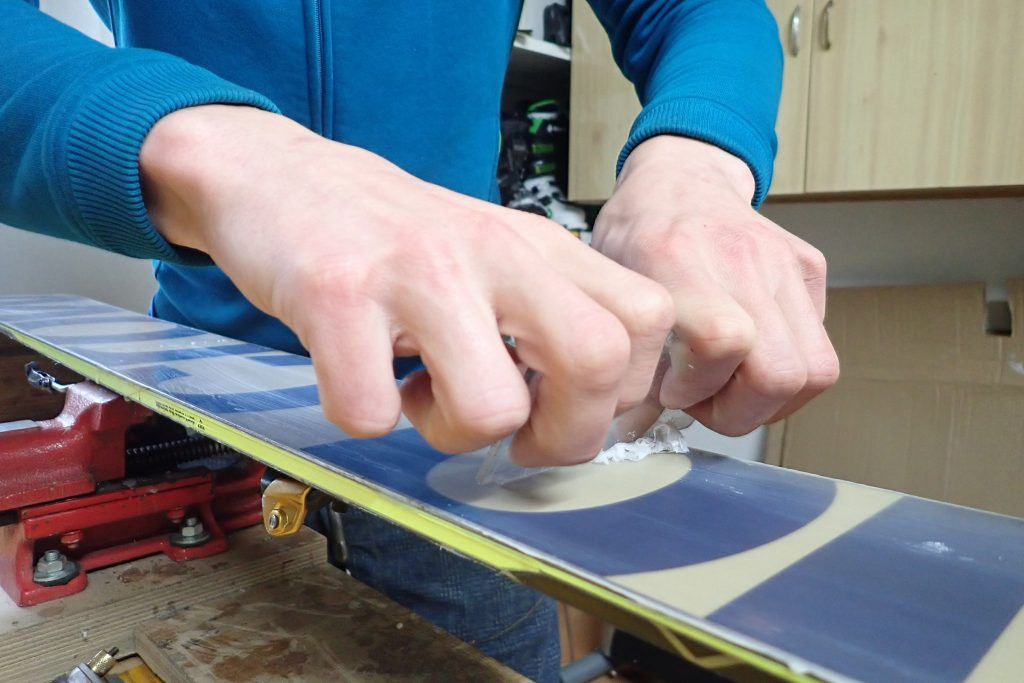 A man scraping wax off of skis.