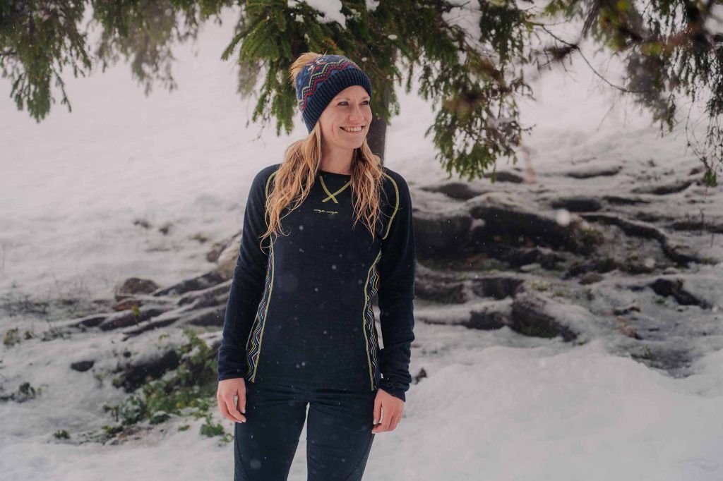 A woman wearing Cami shirt for a winter hike on a snowy hill.