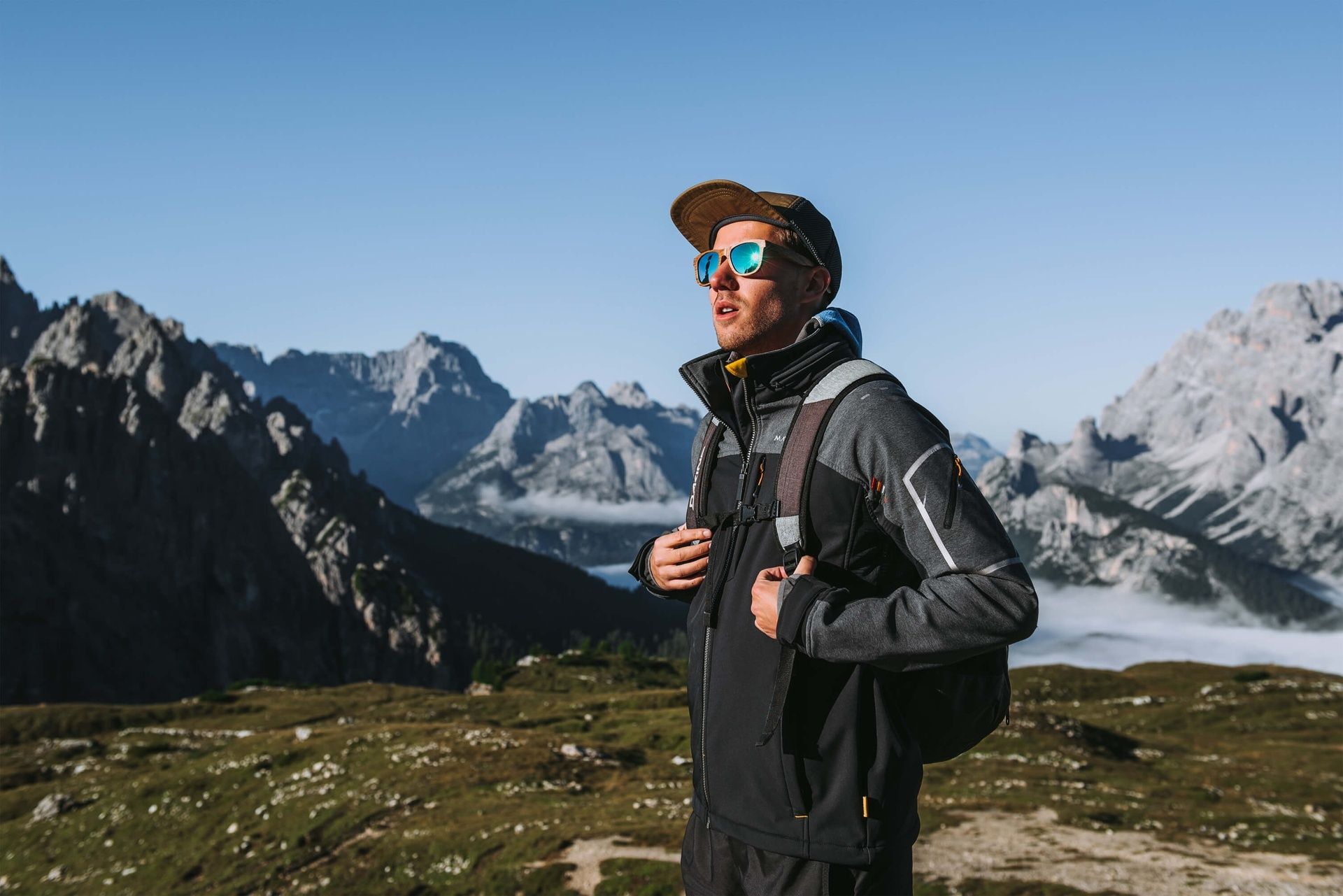 Man with glasses standing on a mountain.