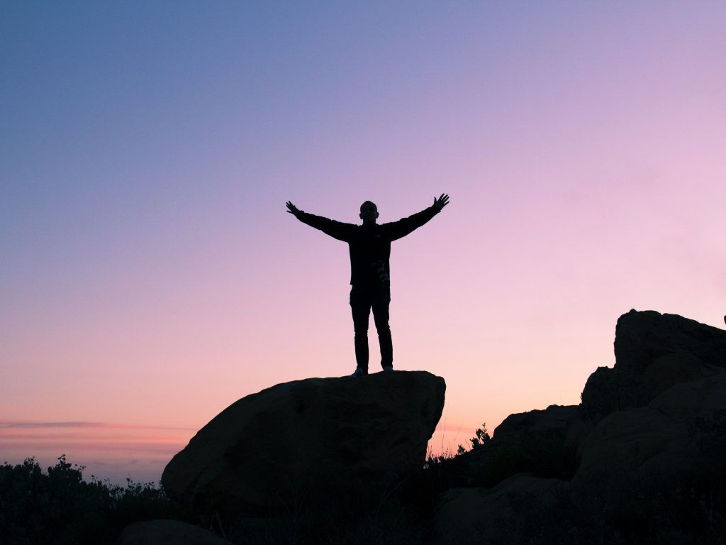 Person on top of a rock feeling free.