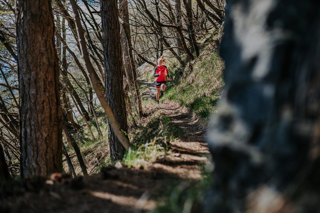 A girl running on a trail in the woods.