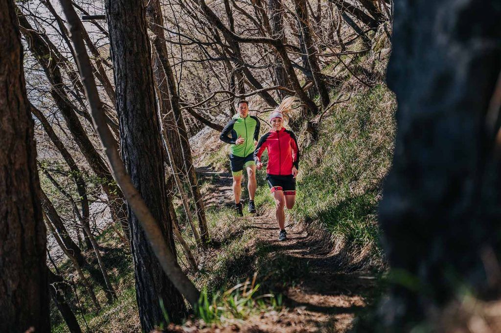 A couple running on a trail in the woods