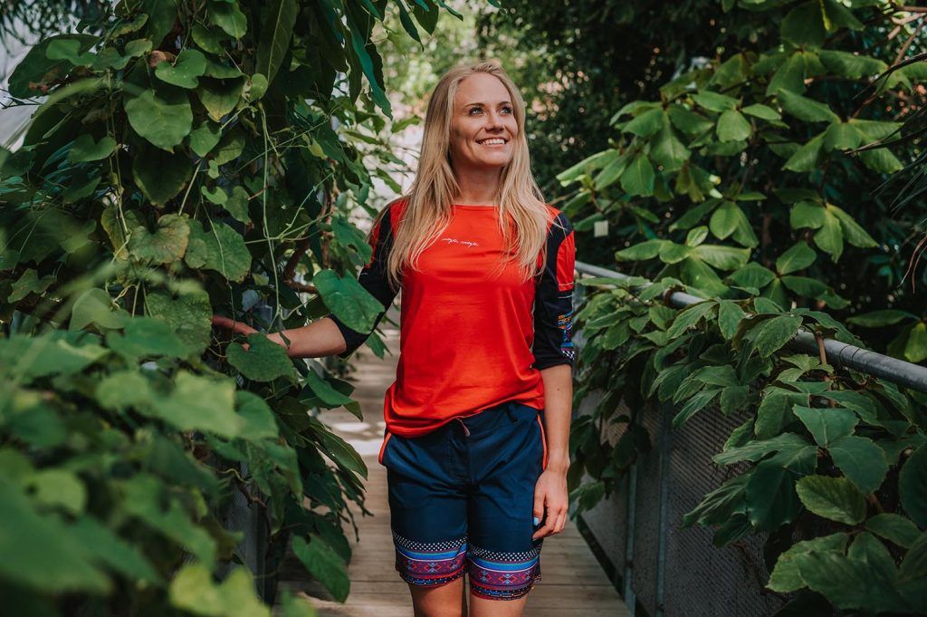 A girl in summer clothing standing in the middle of plants.