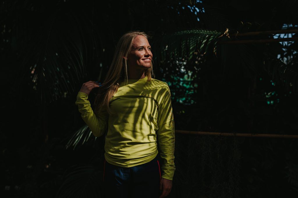 A girl in the jungle standing in the sun.