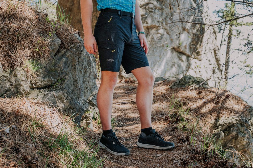 A man in the forest wearing Tupoc bermuda shorts for hiking.