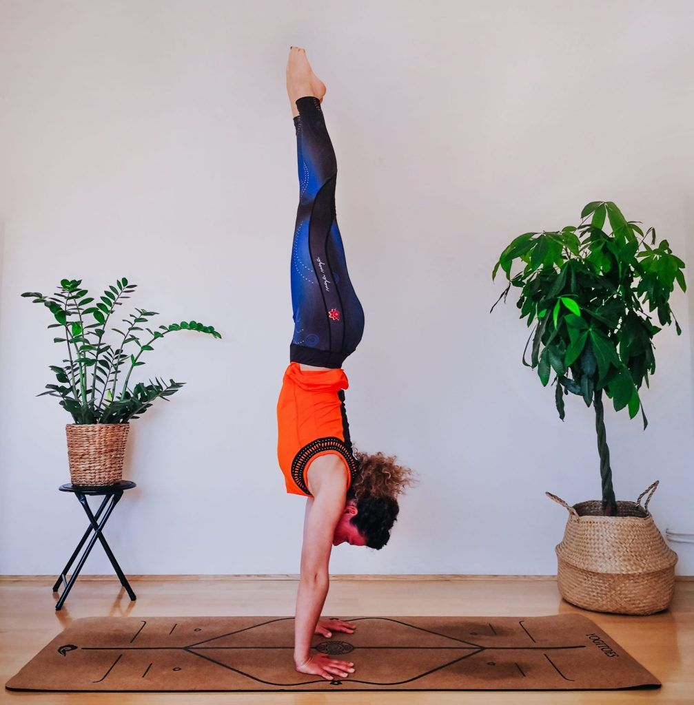 Woman doing handstand on a yoga mat.