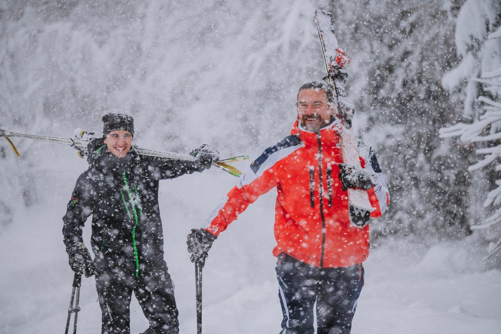 Two men walking in the snow wearing functional ski clothing from MAYA MAYA