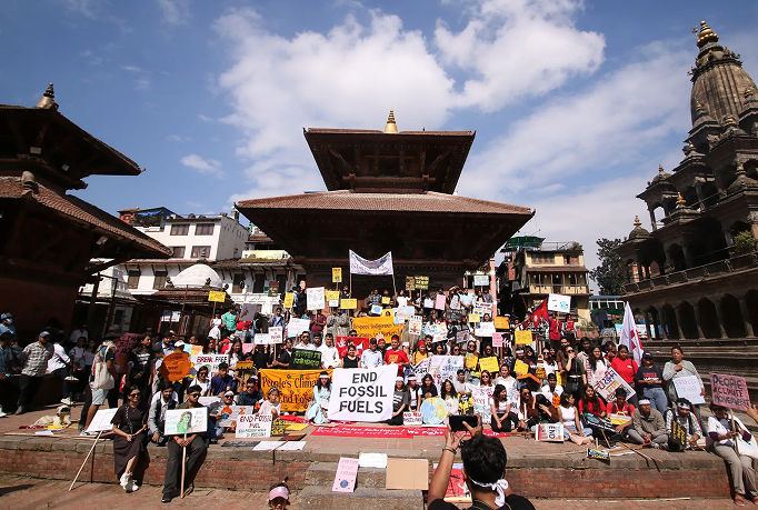 People gathering in a square holding climate action signs