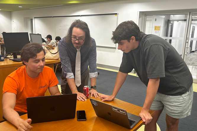 Doug Shook, teaching professor in computer science & engineering, works with students in a CSE1301 studio. (Credit: Channing Suhl)