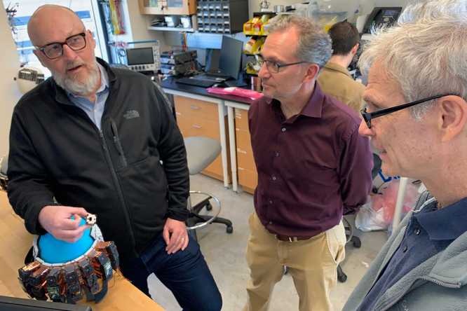 Wearable brain-imaging tech aims to reveal how the brain works in natural, realistic situations. Washington University in St. Louis faculty members (from left) Joseph P. Culver, (holding a piece of a prototype imaging device), Jason Trobaugh, Ed Richter and Adam Eggebrecht, PhD, (not pictured) have received a grant from the NIH to develop and commercialize a brain-imaging cap that uses LED light to gauge brain activity. (Credit: Elizabethe Holland Durando)