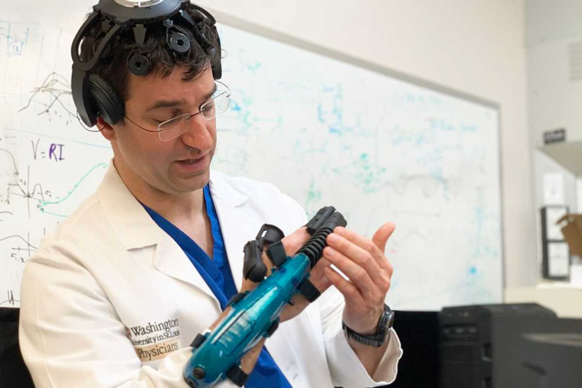 Eric Leuthardt, MD, a professor of neurosurgery at Washington University School of Medicine in St. Louis, models a device that helps people disabled by stroke regain significant control over their arm and hand function by using their minds. Called the IpsiHand Upper Extremity Rehabilitation System, the first-of-its-kind device has received market authorization from the Food and Drug Administration. It was developed by Neurolutions Inc., a Washington University startup company that leverages brain-computer interface technology licensed from the university.