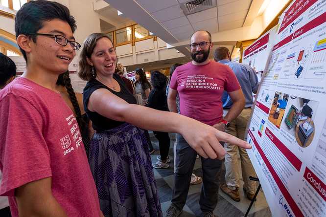 Janie Brennan (center) talks with students Hikari Inaoka (left) and Urban Michaels, both summer research assistants at WashU, at a poster presentation Aug. 1 in Whitaker Hall. Brennan leads the Washington University Summer Engineering Fellowship, which places talented first-generation and limited-income college students in WashU research labs. (Photo: Joe Angeles/WashU)
