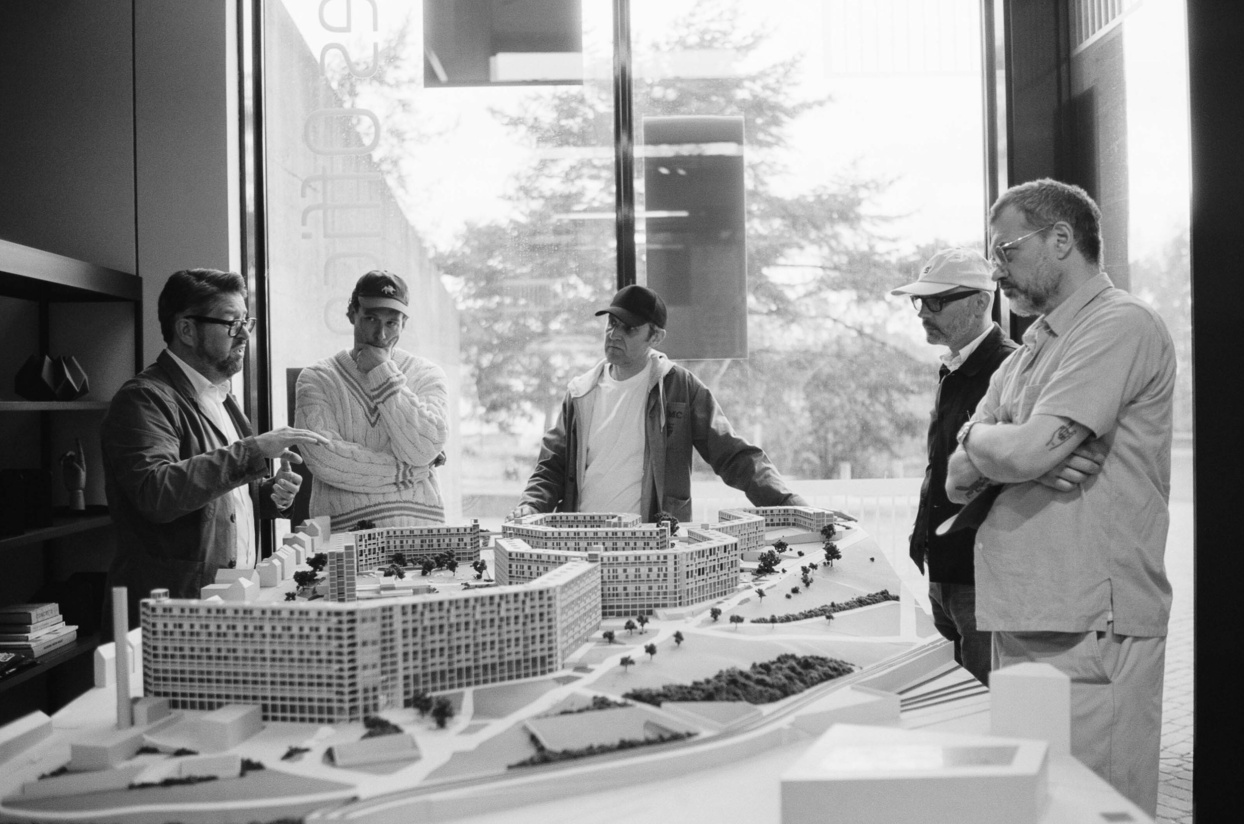 A group of men talking and crowded round a model of Park Hill flats, Sheffield.