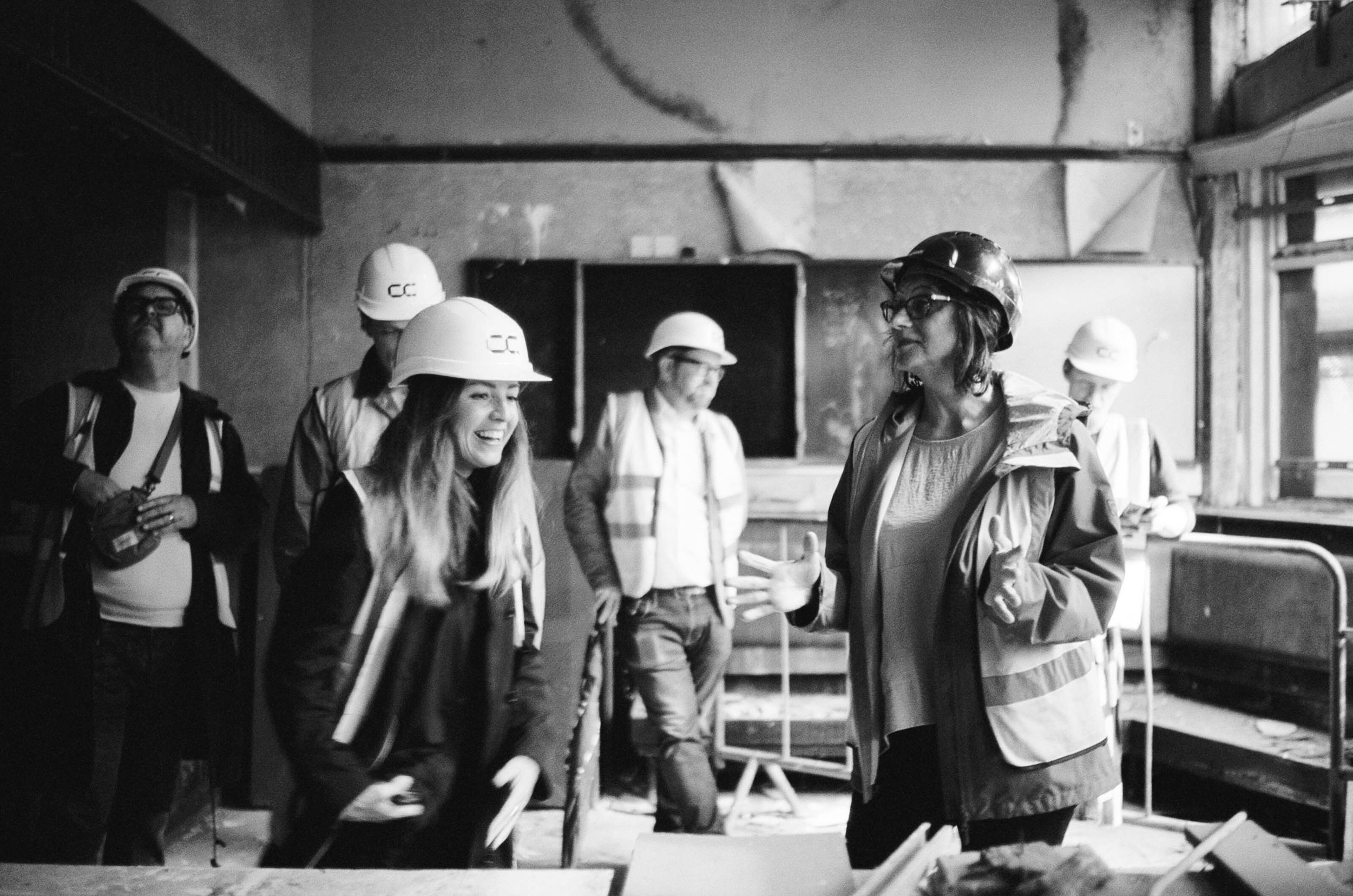 A group of people on a tour wearing hard hats and hi-vis at a former derelict pub in Park Hill, Sheffield.