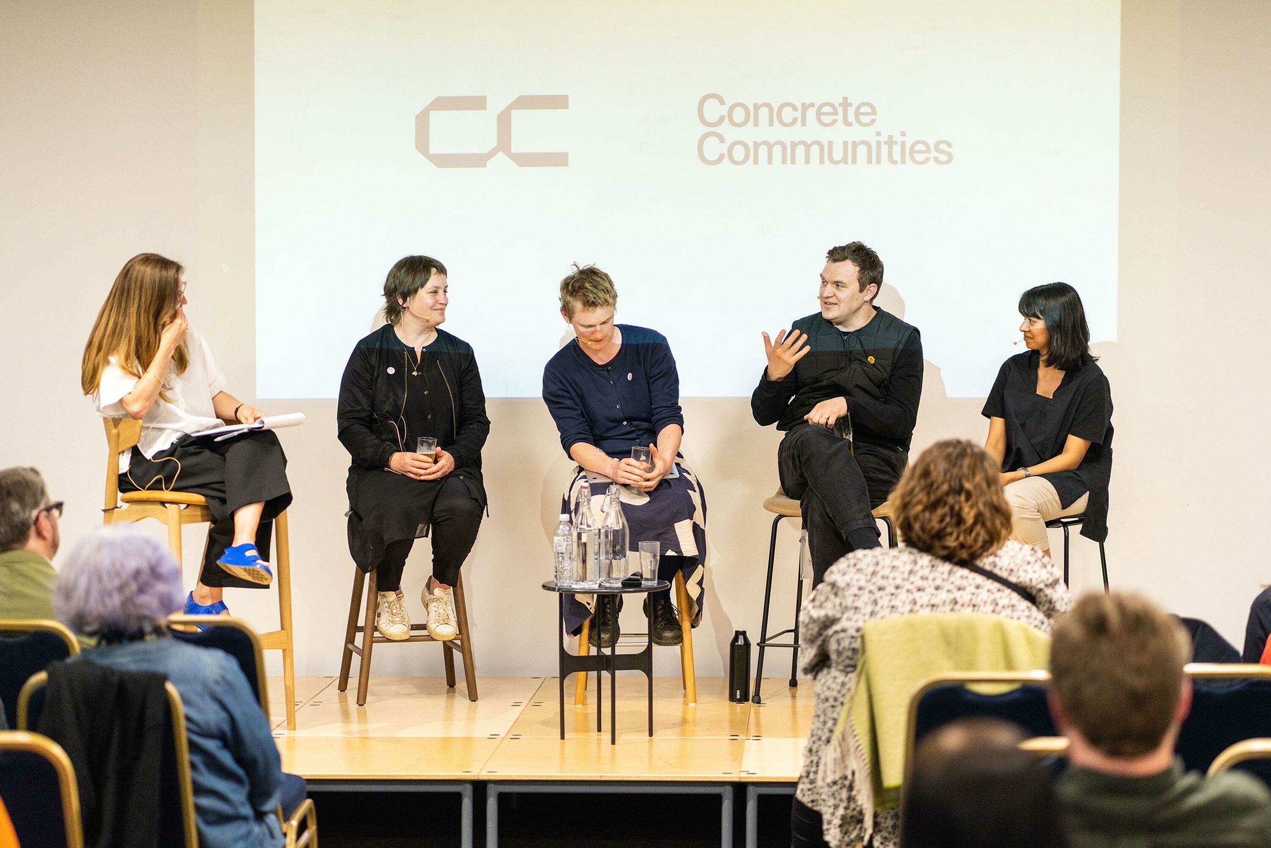 A panel of five people debate on a stage.