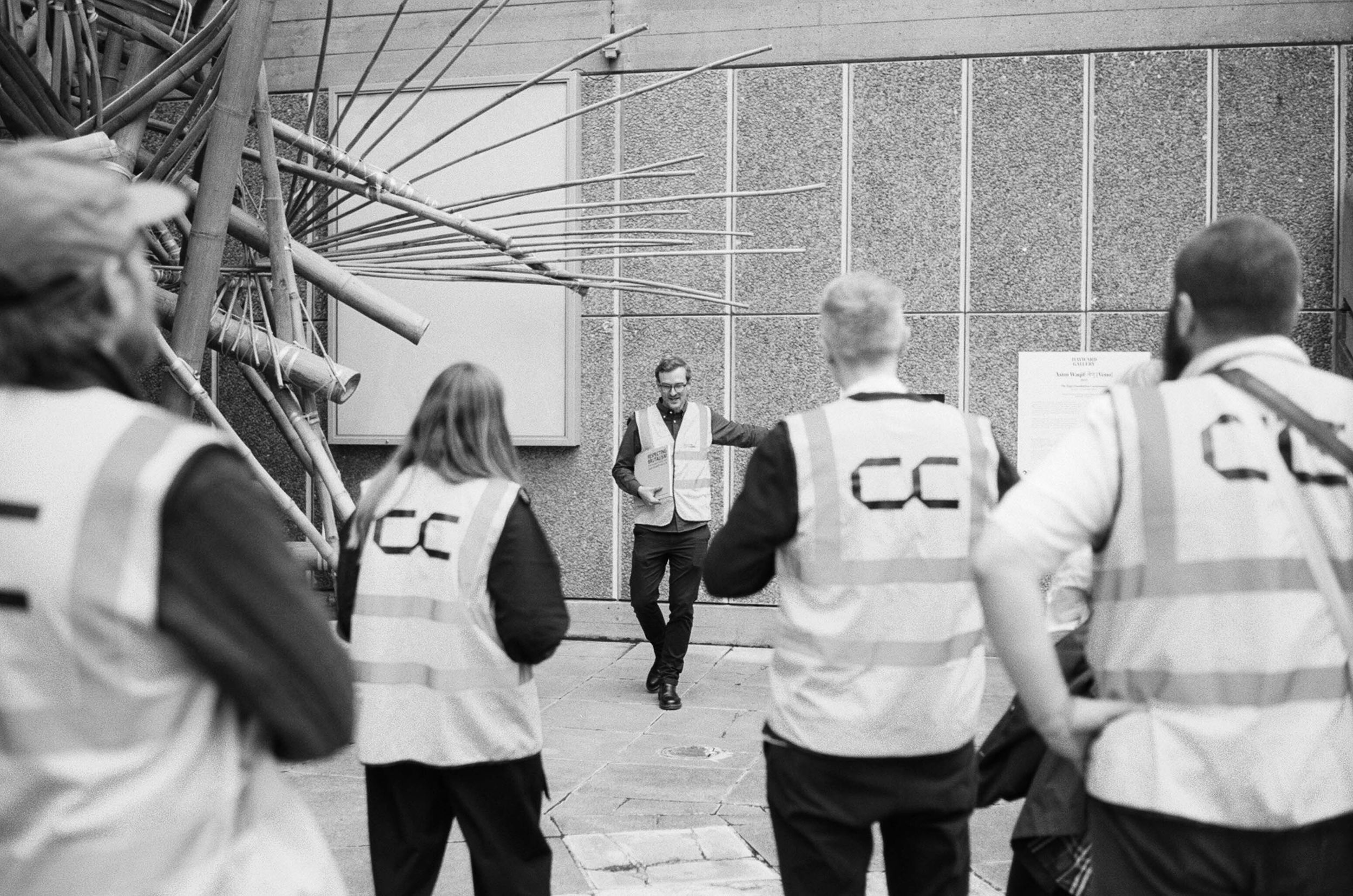 Shot from behind, a group of people wearing hi-vis with Concrete Communities logo printed on the back at the Southbank Centre, London.