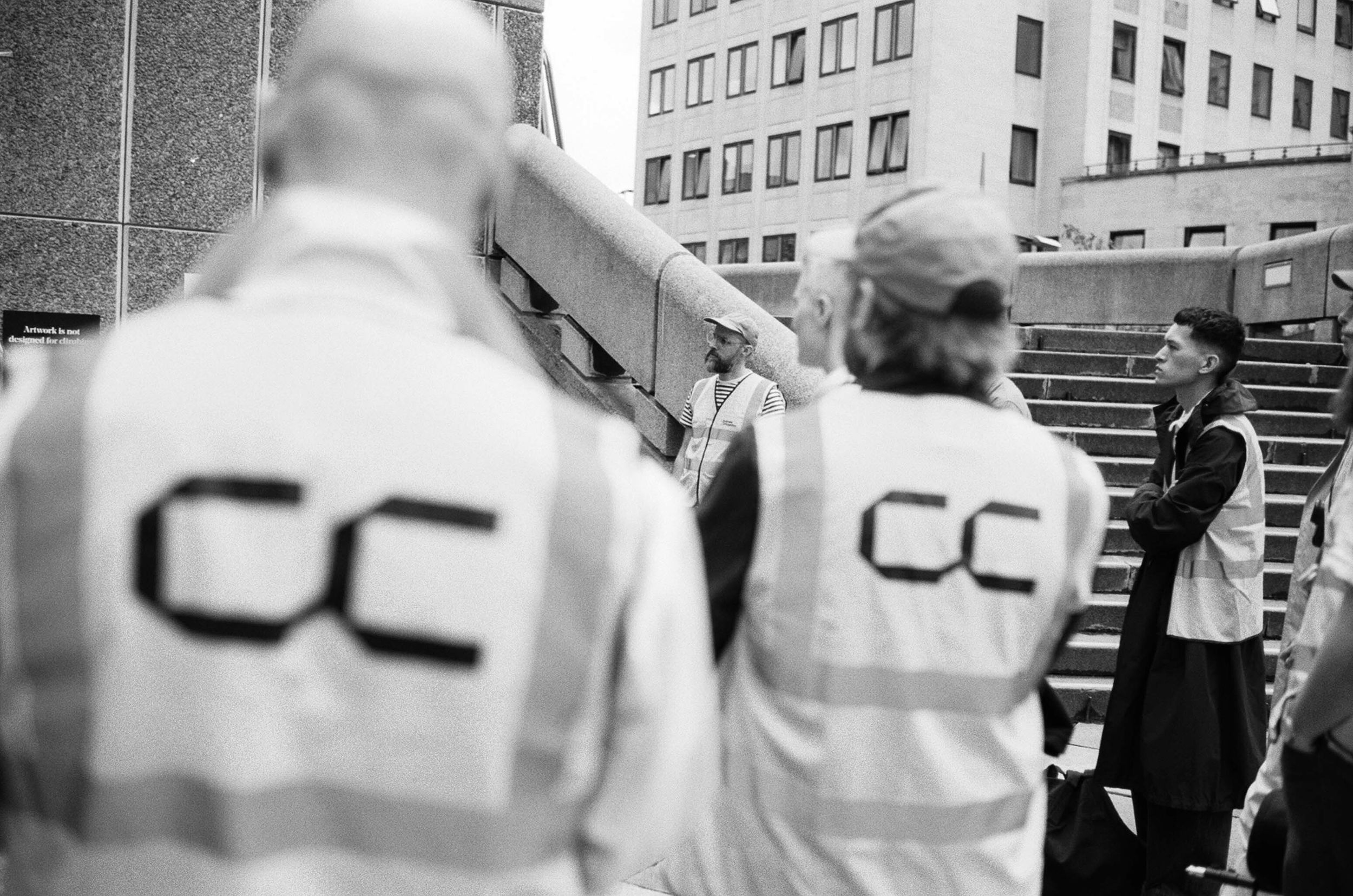 Shot from behind, a group of people wearing hi-vis with Concrete Communities logo printed on the back at the Southbank Centre, London.