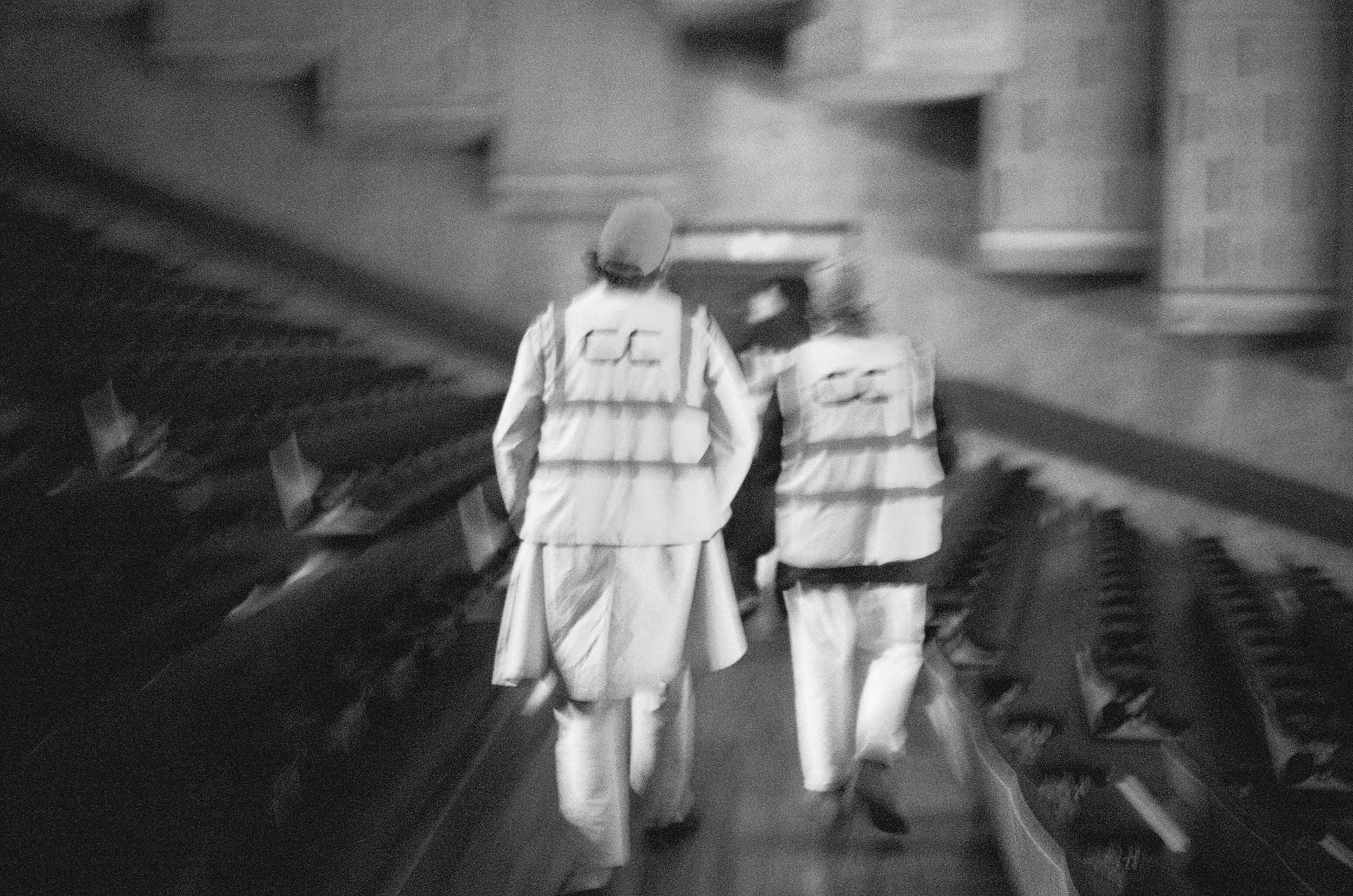 A blurry photo of two people wearing high-vis Concrete Community vests in a theatre hall.