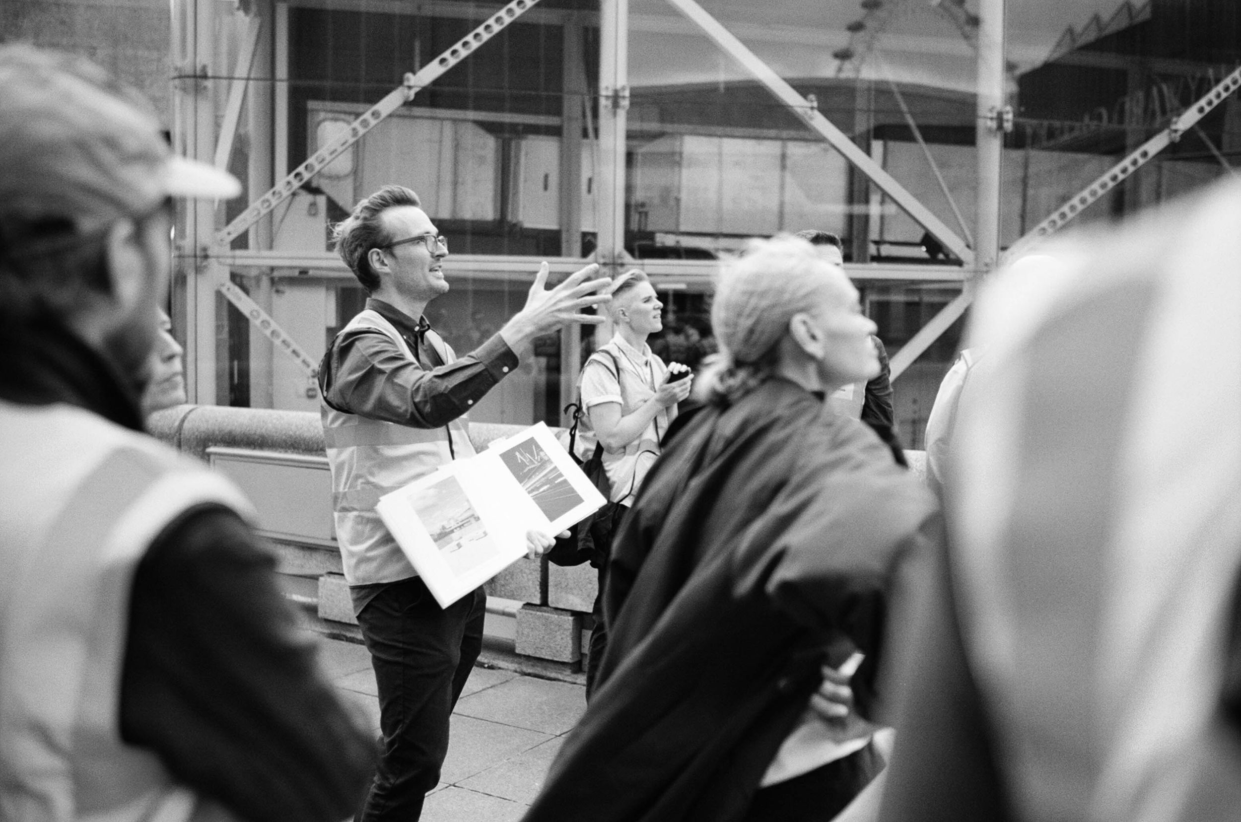 A tour guide holding a book talking to people at the Southbank Centre, London.