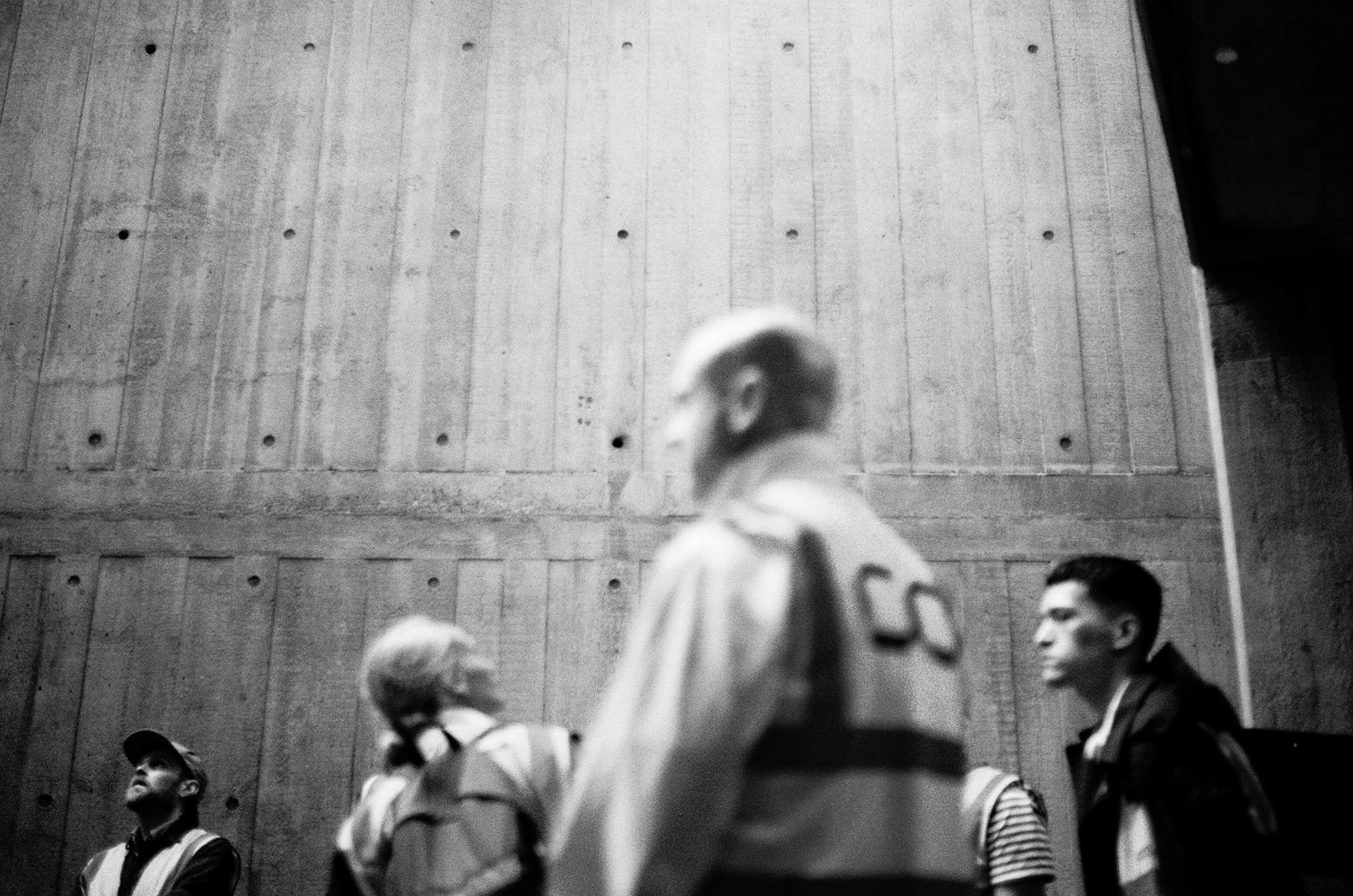 A blurry group of people in front of a board marked concrete wall, at the Southbank Centre, London.