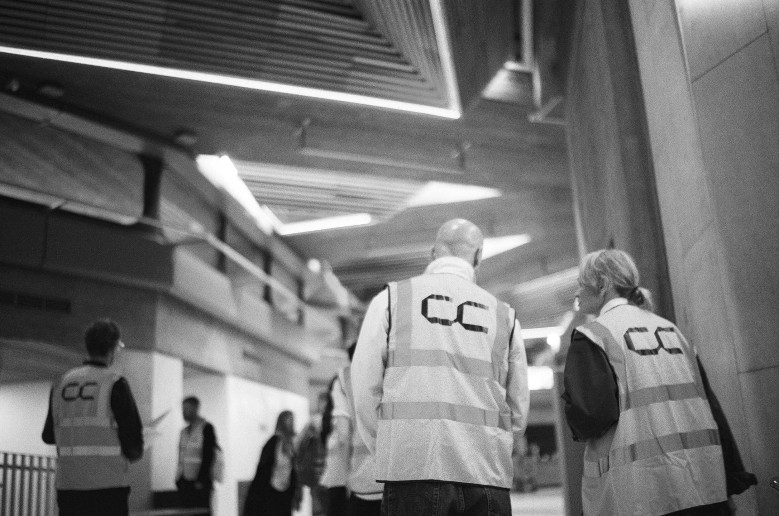 Shot from behind, a group of people wearing hi-vis with Concrete Communities logo printed on the back at the Southbank Centre, London.