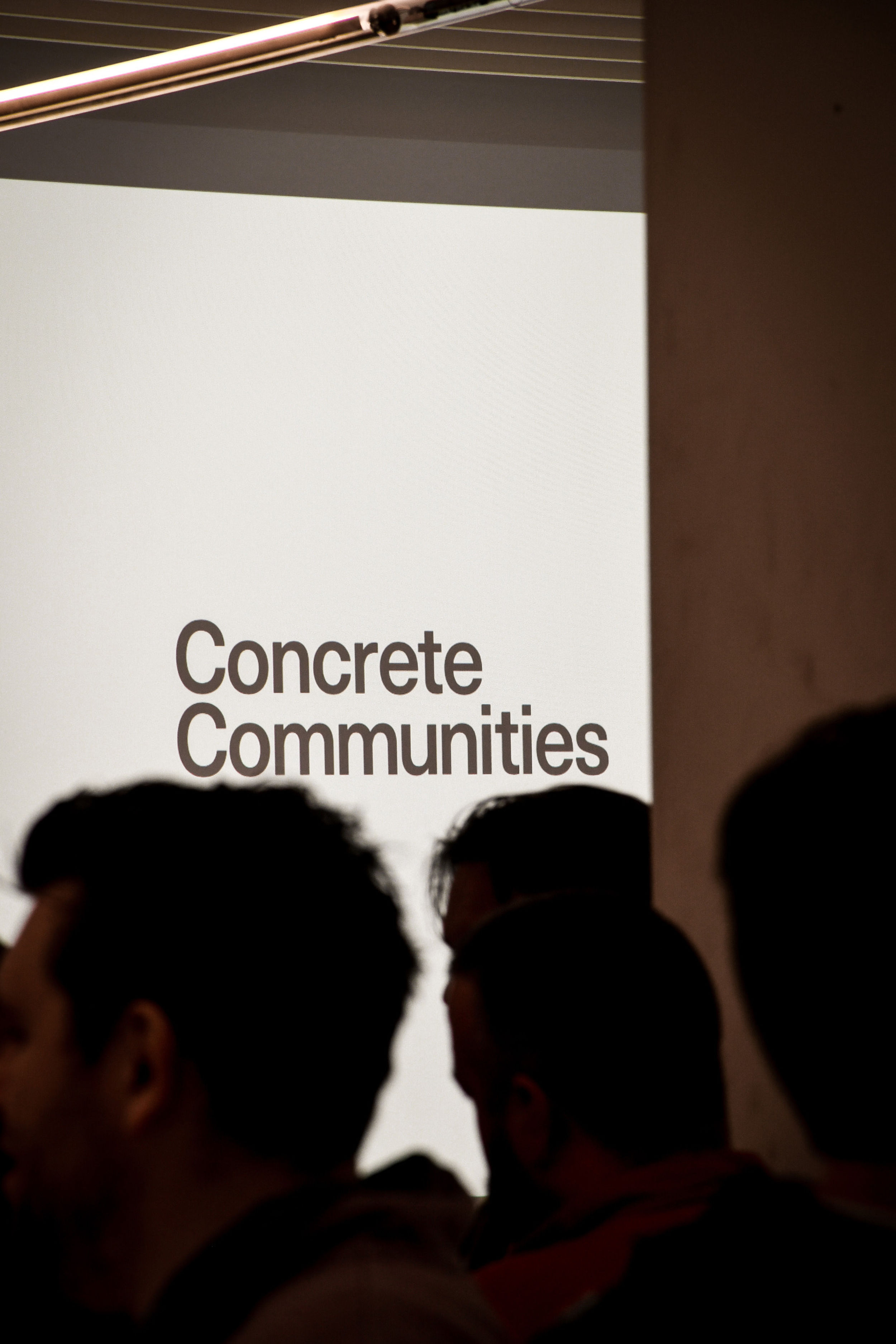 Silhouettes of people in front of a Concrete Communities projected logo.