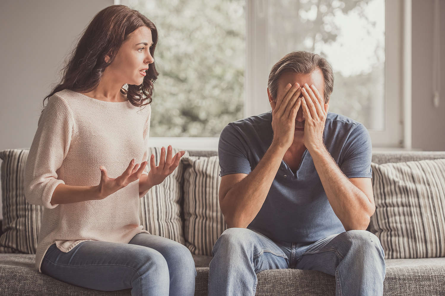 Paar auf dem Sofa in einem emotionalen, konfliktbehafteten Gespräch