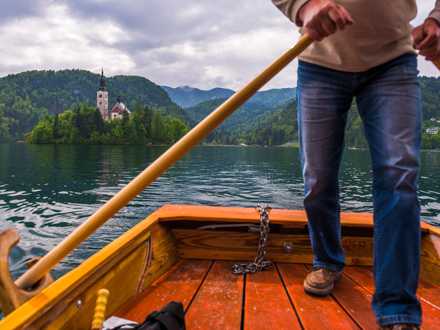 Rowboat on Lake Bled headed toward the island church surrounded by fall foliage. Rowboat on Lake Bled headed toward the island church surrounded by fall foliage.