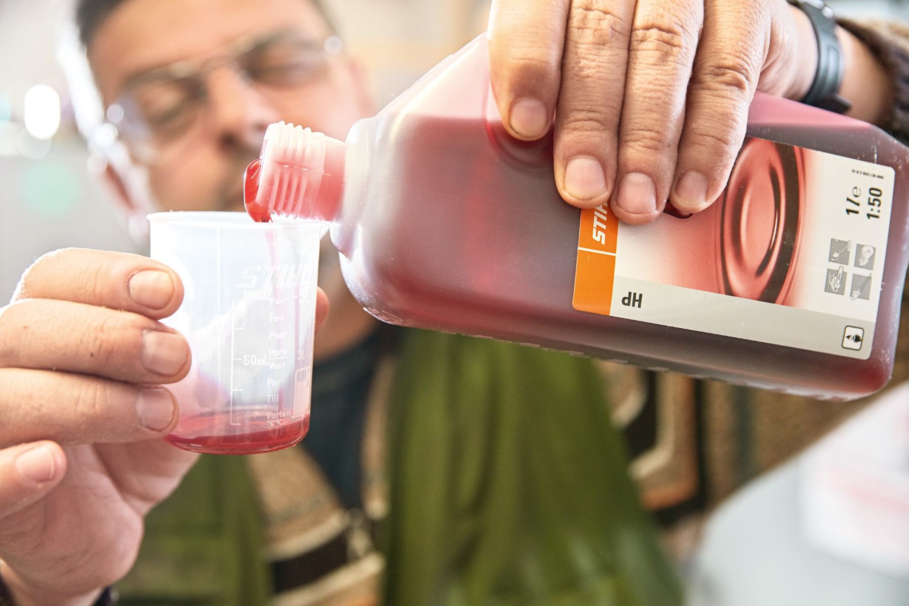 Man pouring STIHL HP two stroke engine oil into small measuring cup