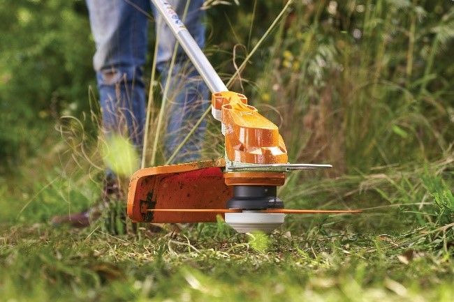 Woman thinning a overgrown garden area with a cordless STIHL brushcutter