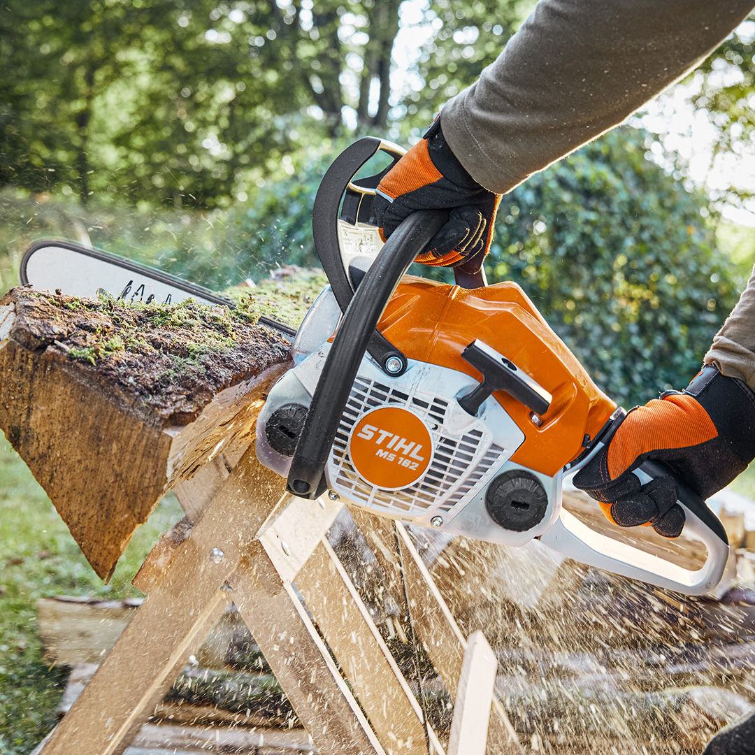 A close-up of the STIHL MS 162 cutting through a wood log placed on a saw horse