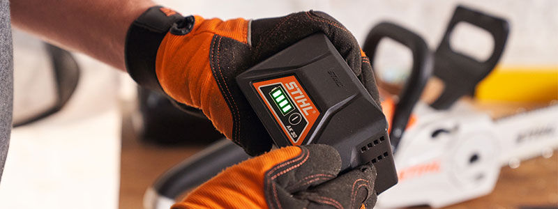 Close-up: Man with Dynamic vent gloves gloves holds battery AK 30 in hand