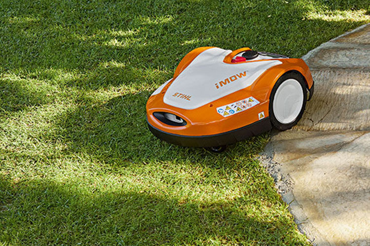 A woman with safety glassing using STIHL Battery Lawn mower to mow her lawn
