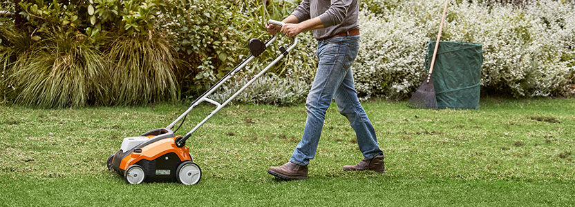 Man with cordless lawn scarifier STIHL RLA 240 on a meadow in his garden