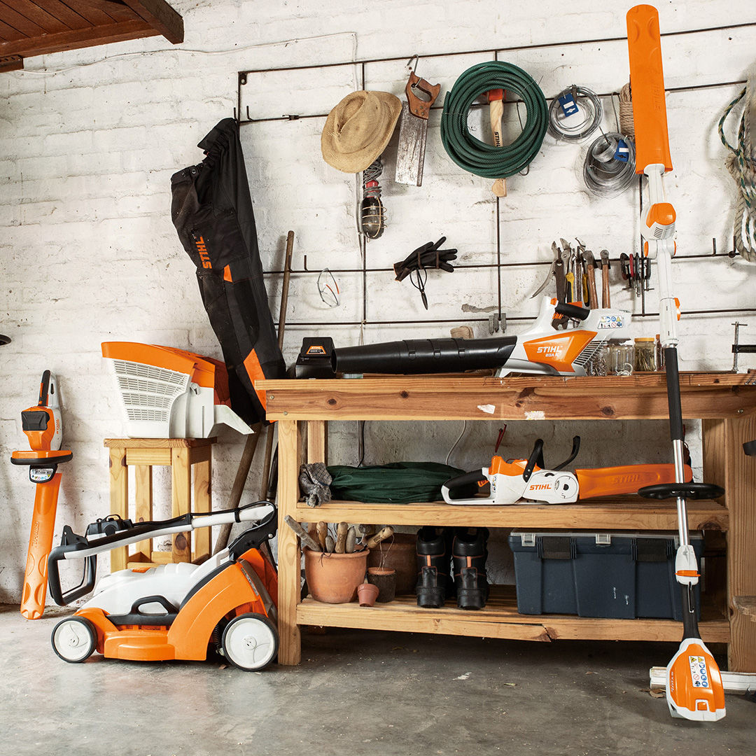 A workshop with various STIHL battery products including a battery lawnmower, battery pole hedge trimmer, a battery blower and a battery chainsaw