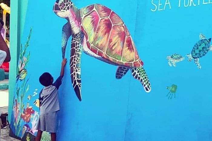 A child shares a sweet moment with a green turtle at our Vaavoshi Sea Turtle Festival.