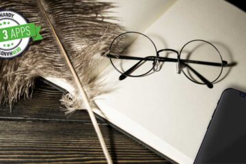 Harry-Potter-Apps: Auf einem Buch mit weißen Seiten liegen ein Smartphone, eine Schreibfeder und eine Brille mit runden Gläsern