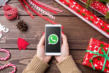 WhatsApp-Weihnachtsgrüße: Handy mit WhatsApp-Logog über einem Weihnachtstisch